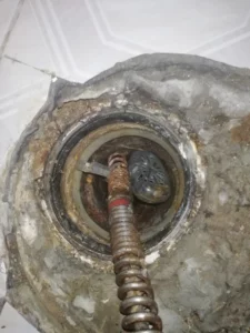 wyjmowanie zawieszki z instalacji kanalizacyjnej za pomocą spirali z odpowiednią końcówką do cofania